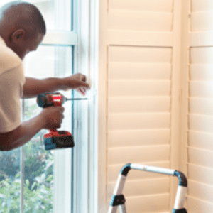 man fixing plantation shutter with drill