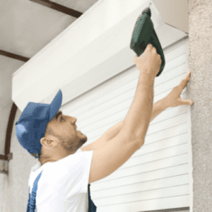 man fixing roller shutter with drill